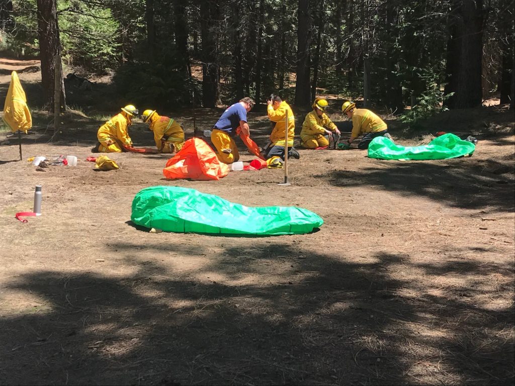 Members of the local volunteer fire agencies practicing their fire shelter deployment